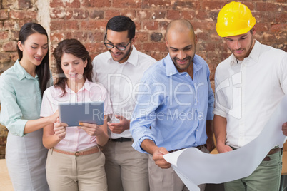 Architect colleagues working on blueprints and digital tablet