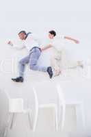 Business people jumping over chairs