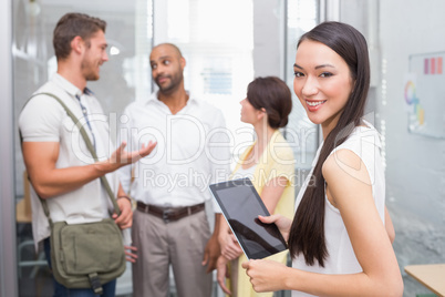 Smiling woman holding tablet in front of her colleague