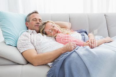 Cute couple napping under a blanket on the couch