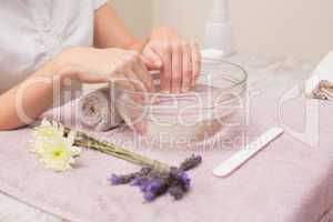 Woman soaking her nails in water bowl