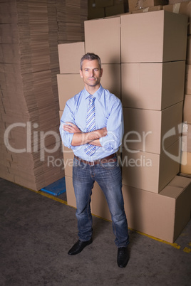 Serious manager with arms crossed in warehouse