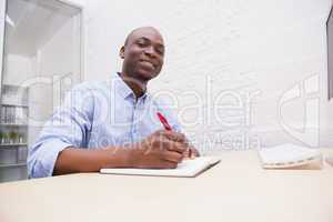 Portrait of a smiling businessman writing notes