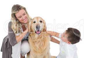 Smiling mother and son petting their golden retriever