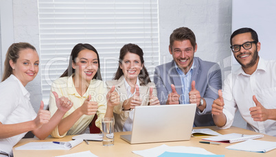 Business team smiling at camera showing thumbs up