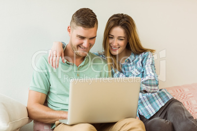 Cute couple relaxing on couch with laptop