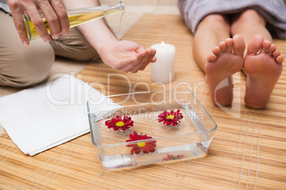 Pedicurist pouring oil into hands