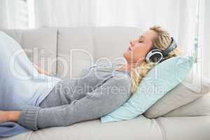 Happy girl listening to music lying on the couch