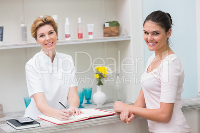 Pretty beautician smiling with client