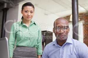 Casual business team looking at camera together at desk