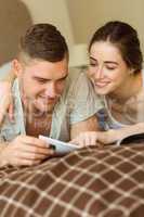 Cute couple reading newspaper in bed