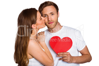 Woman kissing man as he holds heart