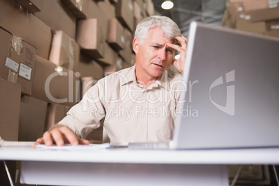 Worried warehouse manager with laptop