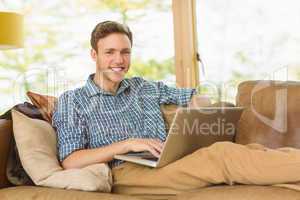 Young man relaxing on his couch with laptop