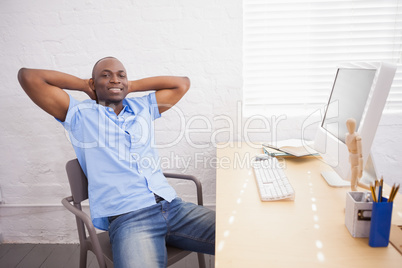 Businessman sitting with hands behind head at desk