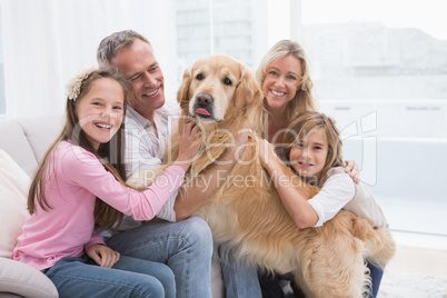 Cute family petting their golden retriever on the couch