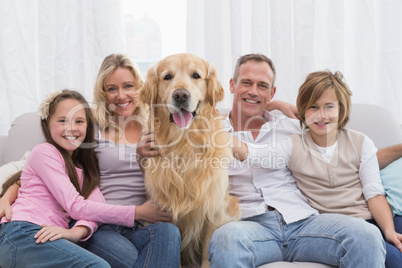 Cute family relaxing together on the couch with their dog