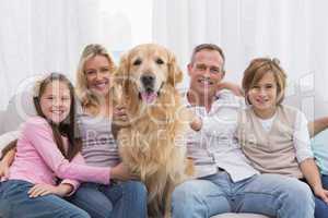 Cute family relaxing together on the couch with their dog
