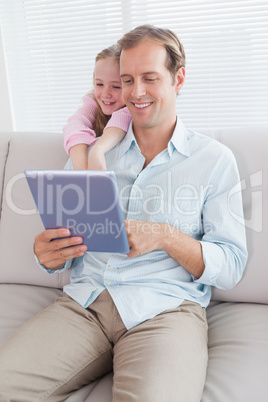 Casual father and daughter using tablet on the couch