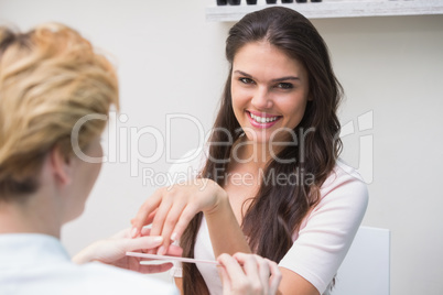 Pretty nail technician giving manicure to customer