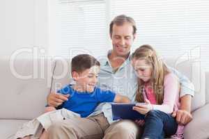 Casual father and children using tablet on the couch