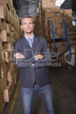 Serious manager with arms crossed in warehouse