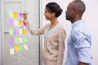 Creative businesswoman writing on sticky notes on window