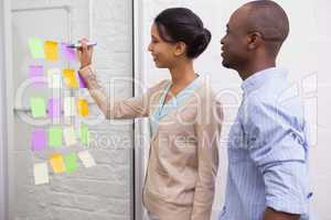 Creative businesswoman writing on sticky notes on window