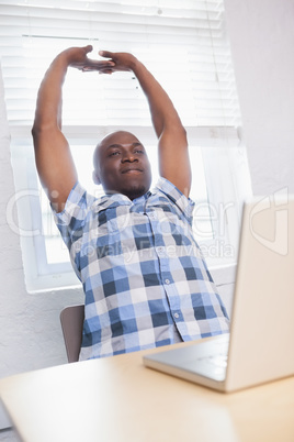 Businessman sitting with arms raised at desk Businessman sitting with arms raised at desk
