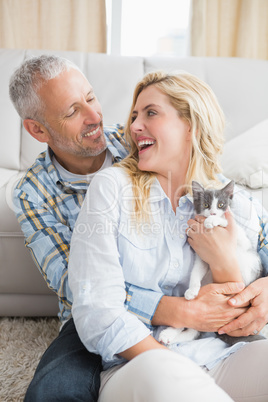 Happy couple with their kitten on the floor