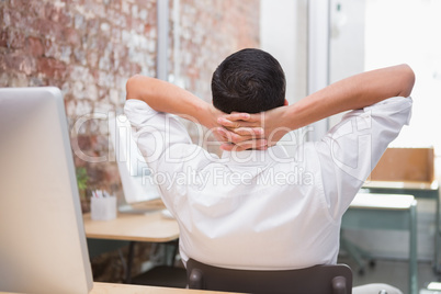 Businessman with hands behind head at desk