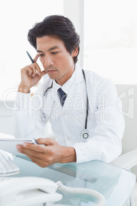 Serious looking doctor reading notes