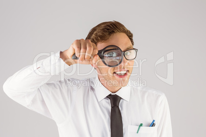 Geeky businessman looking through magnifying glass