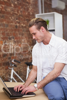 Happy man sitting on the table typing on his laptop