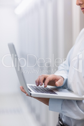 Mid section of a technician typing on his notebook