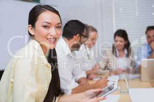 Businesswoman smiling at camera with team behind her