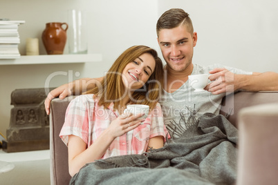 Cute couple relaxing on couch with coffee