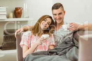 Cute couple relaxing on couch with coffee