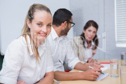 Businesswoman smiling at camera with team behind her