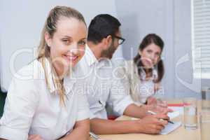 Businesswoman smiling at camera with team behind her