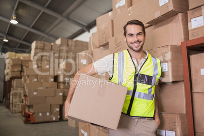 Worker carrying box in warehouse