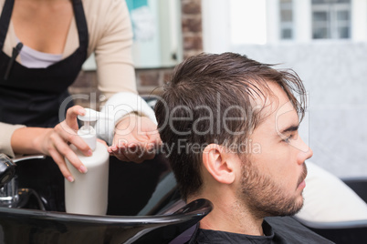 Hair stylist putting conditioner in mans hair