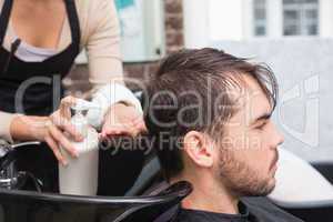 Hair stylist putting conditioner in mans hair