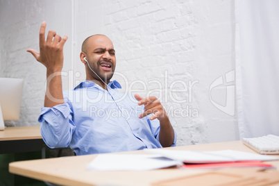 Businessman listening music while playing air guitar in office