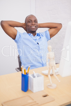 Businessman sitting with hands behind head at desk
