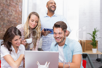 Business team laughing together in front of the laptop Business team laughing together in front of the laptop