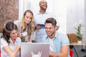 Business team laughing together in front of the laptop