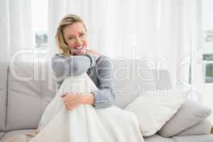 Pretty casual woman sitting on couch under a blanket