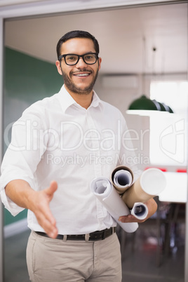Casual architect smiling at camera holding blueprints