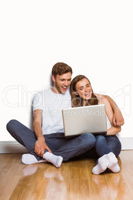 Young couple using laptop on floor